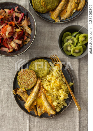 A healthy and flavorful breakfast with turmeric rice, ocean fish, broccoli pancakes, and a roasted vegetable salad, perfect for fueling your day with protein and healthy fats 128200803