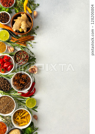 Various cooking spices and herbs spread across a neutral gray background, showcasing their rich, natural tones, top view and copy space 128200804