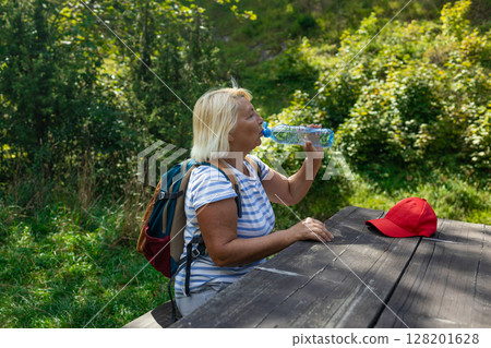 Senior Woman Hydrating During Forest Hike Senior Woman Hydrating During Forest Hike 128201628