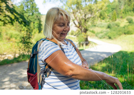 Senior Woman Applying Cream or Repellent During Hike 128201633