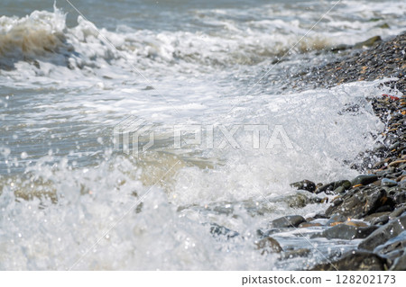 Sea water splashing over the stones on the beach 128202173