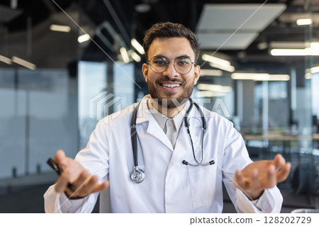 Doctor smiling during video call in modern office setting, wearing a stethoscope, conveying approachability and professionalism. Perfect for healthcare and telemedicine concepts. Doctor smiling during video call in modern office setting, wearing a stethoscope, conveying approachability and professionalism. Perfect for healthcare and telemedicine concepts. 128202729