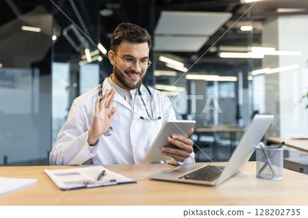 Smiling doctor wearing glasses and white coat engaged in virtual meeting on tablet. Modern technology enhances healthcare consultations for remote patients. Smiling doctor wearing glasses and white coat engaged in virtual meeting on tablet. Modern technology enhances healthcare consultations for remote patients. 128202735