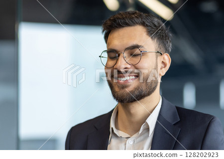 Mature businessman smiling with closed eyes, radiating inspiration and contentment. Dressed in formal attire with a beaming smile, he embodies professional positivity. Mature businessman smiling with closed eyes, radiating inspiration and contentment. Dressed in formal attire with a beaming smile, he embodies professional positivity. 128202923