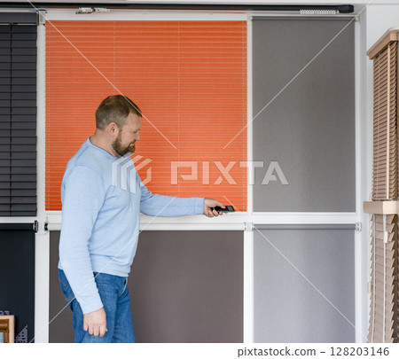 Man operates roller blinds in showroom Man operates roller blinds in showroom 128203146