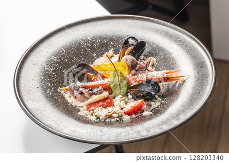 A gourmet seafood risotto with shrimp, mussels, squid, parmesan, and fresh herbs, elegantly plated and garnished with citrus and microgreens A gourmet seafood risotto with shrimp, mussels, squid, parmesan, and fresh herbs, elegantly plated and garnished with citrus and microgreens 128203340