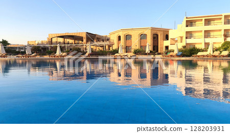 A tranquil resort by the Red Sea in Egypt. The scene features a large swimming pool reflecting the buildings and clear blue sky. It's a perfect summer getaway. 128203931