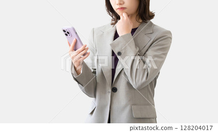 Woman/businesswoman thinking while looking at smartphone Woman/businesswoman thinking while looking at smartphone 128204017