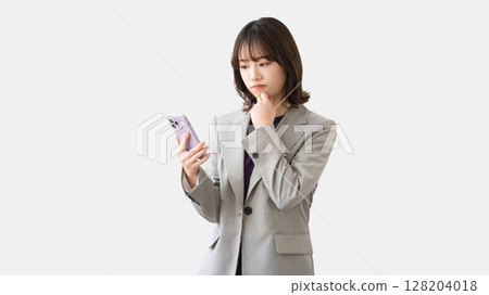 Woman/businesswoman thinking while looking at smartphone Woman/businesswoman thinking while looking at smartphone 128204018