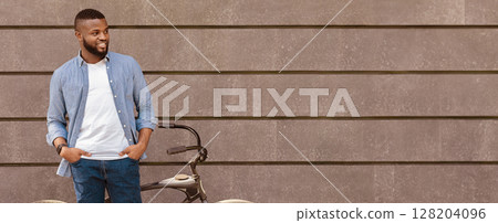 Handsome black man with bicycle over gray wall background outdoors, panorama with copy space Handsome black man with bicycle over gray wall background outdoors, panorama with copy space 128204096
