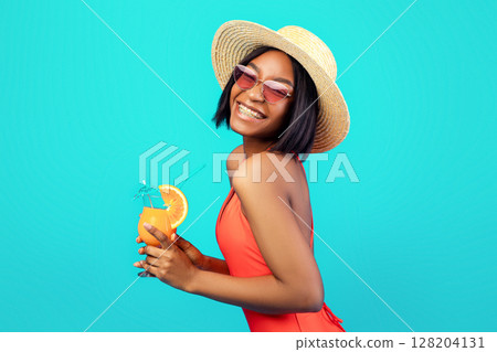 Attractive black woman in bikini drinking cool refreshing tropical cocktail on blue studio background. Portrait of sexy millennial lady enjoying yummy exotic drink on summer vacation Attractive black woman in bikini drinking cool refreshing tropical cocktail on blue studio background. Portrait of sexy millennial lady enjoying yummy exotic drink on summer vacation 128204131