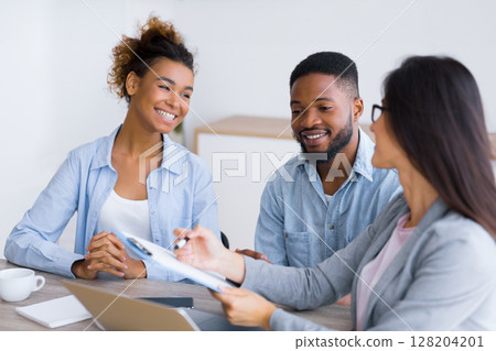 Financial Consultation. Cheerful Black Couple Smiling And Listening To Their Investment Advisor In Office. Selective focus 128204201