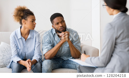 Marital Therapy. Black Couple Listening To Counselor's Advice Sitting On Couch In Office. Marital Therapy. Black Couple Listening To Counselor's Advice Sitting On Couch In Office. 128204218
