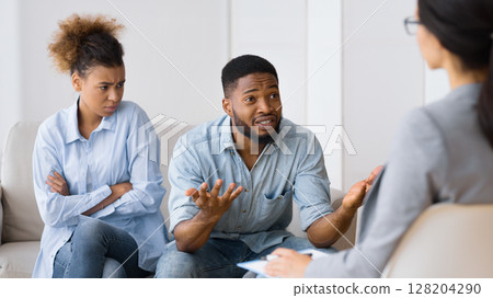 Marriage Therapy Session. African American Husband Sitting Next To His Displeased Wife And Talking To Counselor. 128204290