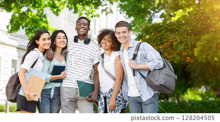 Group of international students posing in front of university, looking at camera and smiling Group of international students posing in front of university, looking at camera and smiling 128204505