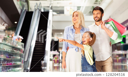 Family Shopping Concept. Little Girl Pointing Finger At Something Walking With Parents In Mall. Free Space For Text 128204516