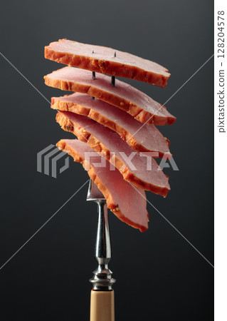Traditional sliced honey glazed ham on a fork. 128204578