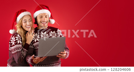 Lovely lady and her boyfriend in winter outfits shopping for Christmas gifts online on laptop, red background 128204606