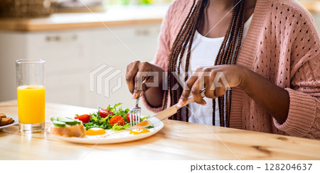 Breakfast Time. Happy African Lady Eating Tasty Healthy Meal In Kitchen, Smiling Black Woman Using Fork And Knife While Enjoying Delicious Food, Having Fresh Salad, Eggs And Sandwiches, Cropped Breakfast Time. Happy African Lady Eating Tasty Healthy Meal In Kitchen, Smiling Black Woman Using Fork And Knife While Enjoying Delicious Food, Having Fresh Salad, Eggs And Sandwiches, Cropped 128204637