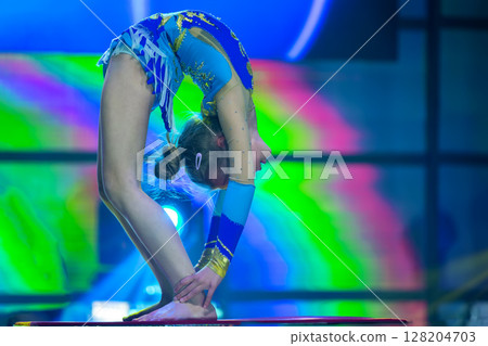 Plastic little girl gymnast. A child with a flexible body performs on stage. 128204703
