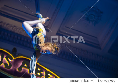 The girl performs acrobatic numbers on the canvases. A small circus artist performs on the canvases of acrobats. Child perform acrobatic elements in the air The girl performs acrobatic numbers on the canvases. A small circus artist performs on the canvases of acrobats. Child perform acrobatic elements in the air 128204709