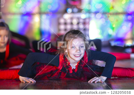 A funny little girl with a good stretch does a dance on stage. A funny little girl with a good stretch does a dance on stage. 128205038