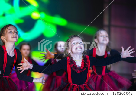Little girls are performing a dance number. Dance for Helovinna in red suits. Girl dancing. Emotional performance of a children's dance group. Little girls are performing a dance number. Dance for Helovinna in red suits. Girl dancing. Emotional performance of a children's dance group. 128205042