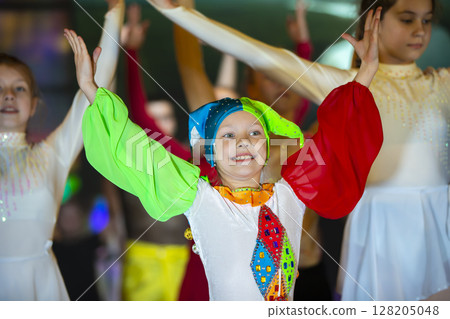 A funny girl is performing a dance in a clown costume. 128205048