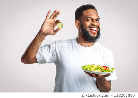 Joyful Black Man Holding Vegetable Salad Gesturing Okay Choosing Healthy Food Standing Over White Studio Background, Smiling To Camera. Slimming Nutrition And Male Weight Loss 128205090