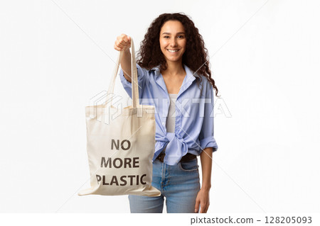 No More Plastic. Smiling Lady Showing Eco Shopper Bag With Inscription Standing On White Background In Studio. Conscious Consumption And Ecology Protection Concept No More Plastic. Smiling Lady Showing Eco Shopper Bag With Inscription Standing On White Background In Studio. Conscious Consumption And Ecology Protection Concept 128205093