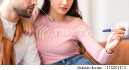 Depressed Arab Couple Holding Negative Pregnancy Test Sitting Together On Sofa At Home. Young Spouses Struggling Infertility And Dreaming To Be Parents. Childbirth Problem Concept. Selective Focus 128205123