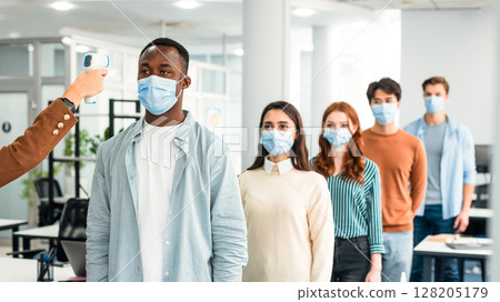 Check Up Measurement. Woman with non-contact laser gun thermometer checking body temperature of multiracial people wearing protective face masks and standing in line at entrance of modern office Check Up Measurement. Woman with non-contact laser gun thermometer checking body temperature of multiracial people wearing protective face masks and standing in line at entrance of modern office 128205179