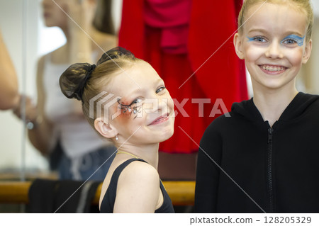 Beautiful little girls performers with make-up on their faces are smiling and looking at the camera. Beautiful little girls performers with make-up on their faces are smiling and looking at the camera. 128205329