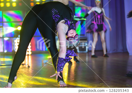 A girl equilibrist with a flexible body shows a difficult number on stage. 128205343
