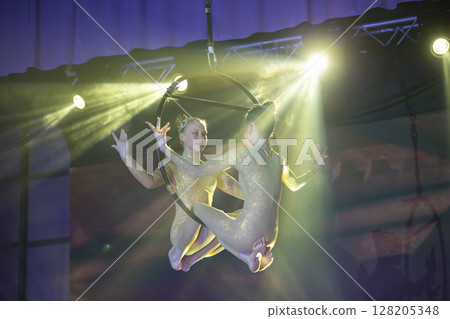 Circus actress acrobat performance. Two girls perform acrobatic elements in the air ring. Circus actress acrobat performance. Two girls perform acrobatic elements in the air ring. 128205348