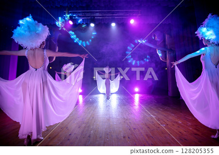 Beautiful girls from the variety show are dancing on stage.Dancers in white dresses perform modern dance cabaret Beautiful girls from the variety show are dancing on stage.Dancers in white dresses perform modern dance cabaret 128205355
