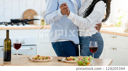 Romantic Moments. Young Happy Black Couple Dancing Together In Kitchen, Affectionate African American Lovers Having Fun While Spending Time At Home, Eating Tasty Food And Drinking Red Wine Romantic Moments. Young Happy Black Couple Dancing Together In Kitchen, Affectionate African American Lovers Having Fun While Spending Time At Home, Eating Tasty Food And Drinking Red Wine 128205394