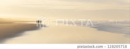 Three individuals walking along a serene beach at sunset, with gentle waves lapping at the shore and a soft golden glow illuminating the scene 128205718