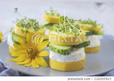 Cucumber and zucchini rolls with cream cheese and microgreens on a plate, healthy food, vegetarian food.  128205923