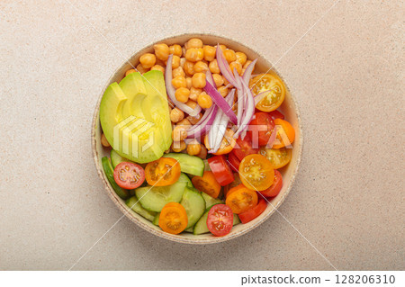 Vibrant vegetarian chickpea salad with fresh vegetables in ceramic bowl top view on light beige background 128206310