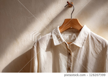 Linen shirt on wooden hanger hanging on wall 128207399