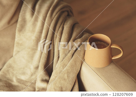 Mug of hot coffee stay on arm of chair by blanket Mug of hot coffee stay on arm of chair by blanket 128207609