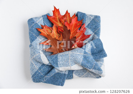 Autumn folded sweater with oak leaves on white background. Top view 128207626