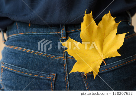 Jeans with autumn maple leaf in pocket. Front view 128207632