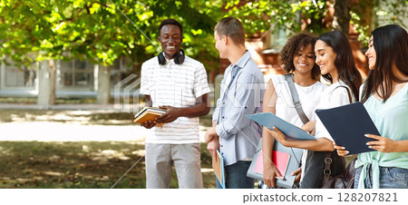 Campus Life. Portrait Of Cheerful Interracial Students Resting Outdoors Between Classes, Chatting And Smiling Campus Life. Portrait Of Cheerful Interracial Students Resting Outdoors Between Classes, Chatting And Smiling 128207821