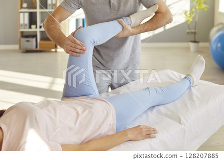 Knee rehabilitation, female leg, knee massage, physical therapy by professional male nurse 128207885