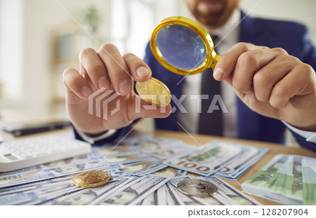 Businessman Studying Bitcoin Gold Coin In Cash Filled Office 128207904