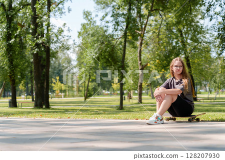 Portrait of a carefree teenage girl dressed in casual summer attire as she casually sits atop a skateboard, embodying the active, adventurous spirit of youth Portrait of a carefree teenage girl dressed in casual summer attire as she casually sits atop a skateboard, embodying the active, adventurous spirit of youth 128207930