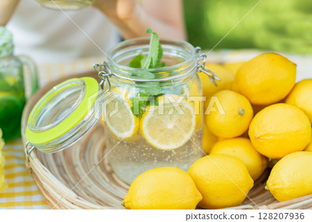 Plate with ripe fresh lemons and lemonade sassy water. Vitamins concept. copy space. Strengthening immunity concept. Tropical fruit. Organic citrus fruits for a healthy diet. 128207936