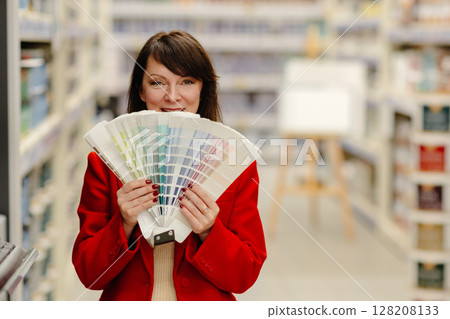Interior designer choosing paint color from swatches in hardware store Interior designer choosing paint color from swatches in hardware store 128208133